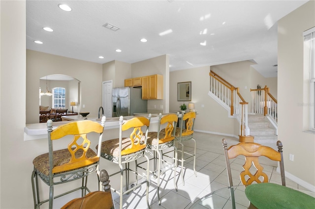 kitchen featuring stainless steel refrigerator with ice dispenser, light brown cabinets, light tile patterned floors, and a wealth of natural light