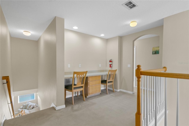 carpeted office space featuring built in desk