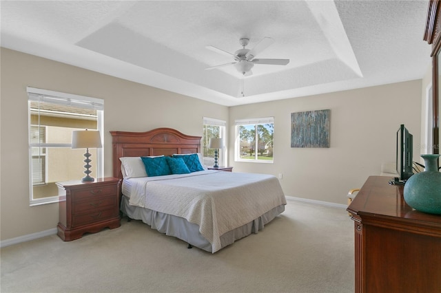 carpeted bedroom with a raised ceiling, ceiling fan, and a textured ceiling