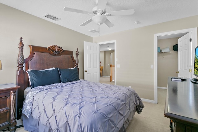 bedroom featuring light carpet, a closet, a spacious closet, and ceiling fan