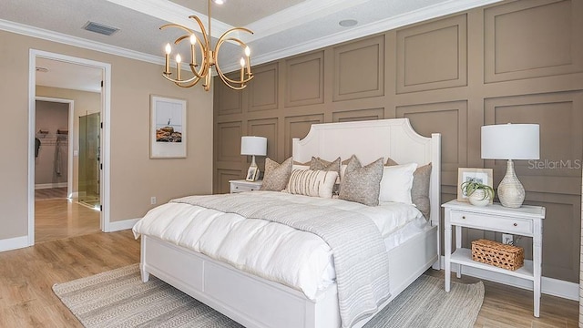 bedroom featuring an inviting chandelier, light hardwood / wood-style flooring, and crown molding