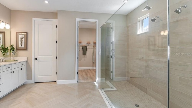 bathroom with a tile shower and vanity