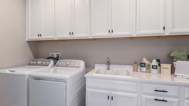 clothes washing area with washer and dryer, sink, and cabinets