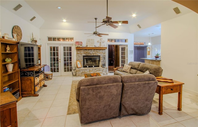 tiled living room featuring ceiling fan, a stone fireplace, lofted ceiling, and french doors