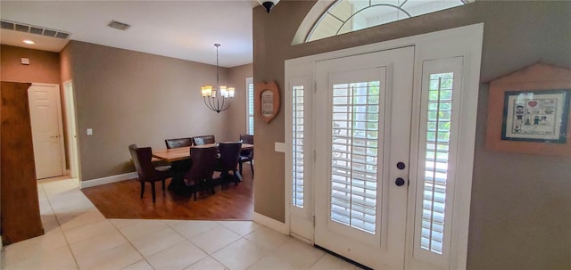 foyer entrance featuring a chandelier, baseboards, tile patterned flooring, and vaulted ceiling