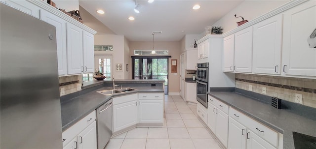 kitchen with stainless steel appliances, dark countertops, a sink, backsplash, and recessed lighting