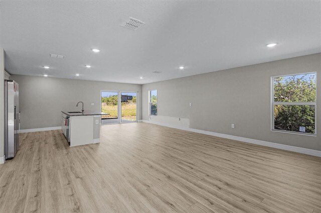 unfurnished living room featuring light hardwood / wood-style flooring and sink