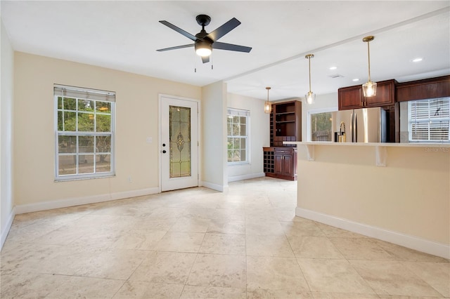 kitchen with a kitchen breakfast bar, stainless steel refrigerator, ceiling fan, and hanging light fixtures