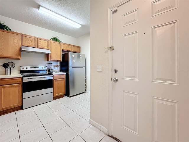 kitchen with a textured ceiling, light tile patterned flooring, and stainless steel appliances