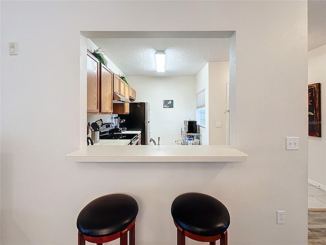 kitchen featuring kitchen peninsula, a breakfast bar, and a textured ceiling