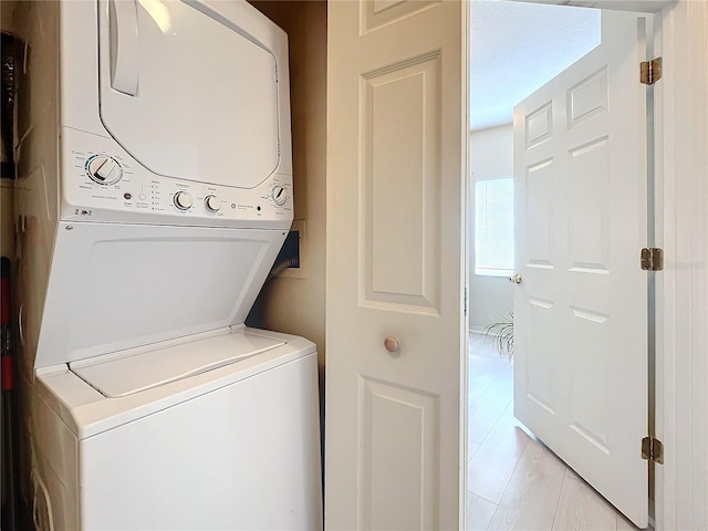 laundry area with light tile patterned floors and stacked washer / drying machine