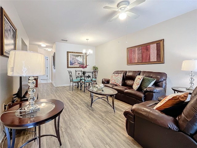 living room with ceiling fan with notable chandelier and light wood-type flooring