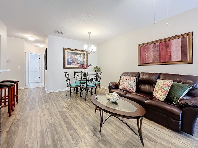 living room with light hardwood / wood-style floors, a textured ceiling, and a chandelier