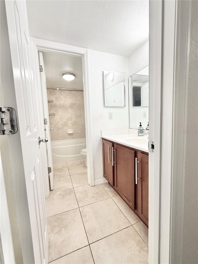 full bathroom with tiled shower / bath combo, vanity, toilet, tile patterned floors, and a textured ceiling