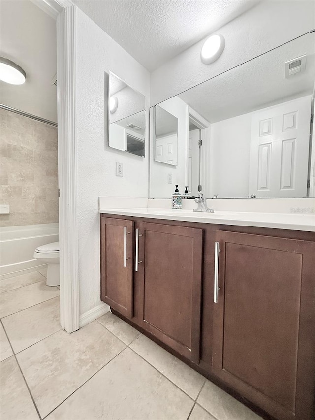 full bathroom with tile patterned flooring, tiled shower / bath combo, vanity, a textured ceiling, and toilet