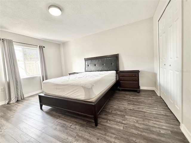 bedroom featuring dark wood-type flooring, a closet, and a textured ceiling