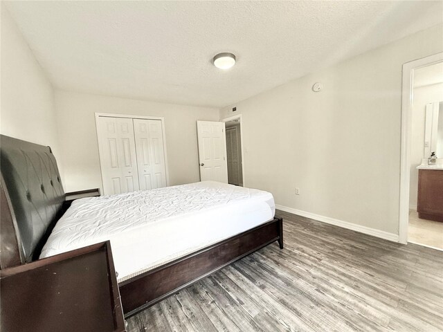 bedroom with a closet, connected bathroom, hardwood / wood-style floors, and a textured ceiling