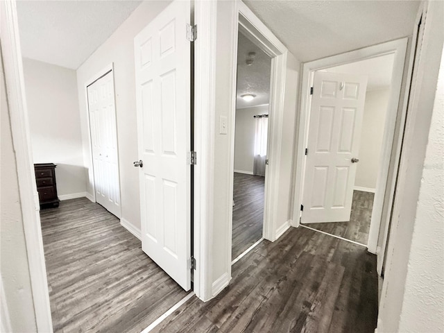 corridor with dark hardwood / wood-style floors and a textured ceiling