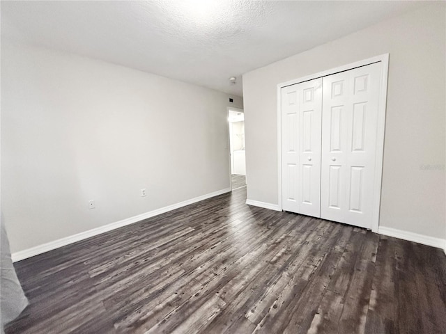 unfurnished bedroom featuring dark hardwood / wood-style flooring, a closet, and a textured ceiling