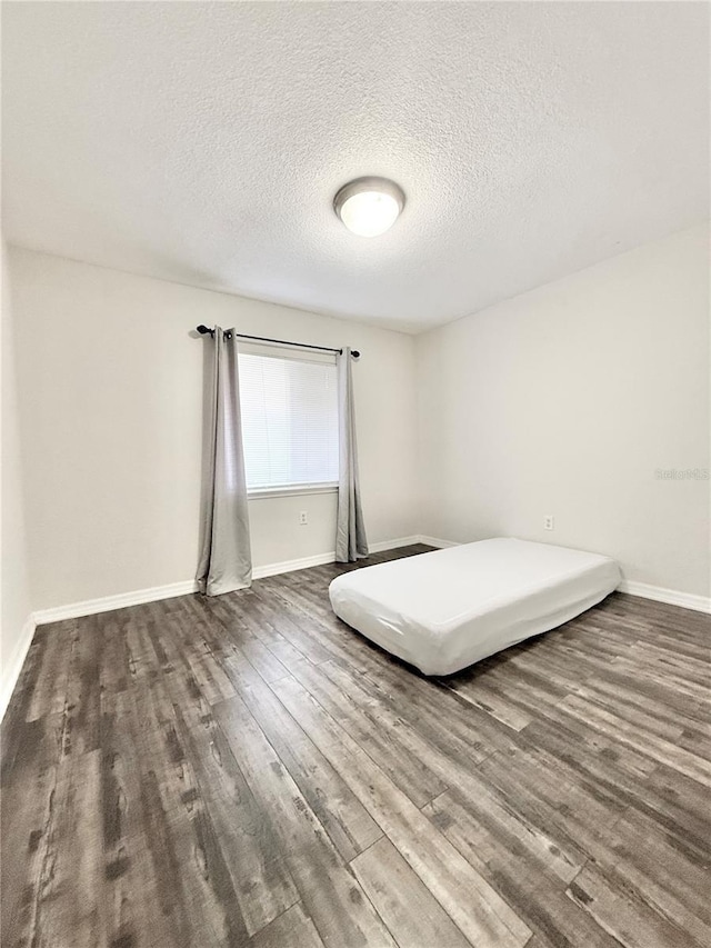 unfurnished bedroom with hardwood / wood-style flooring and a textured ceiling