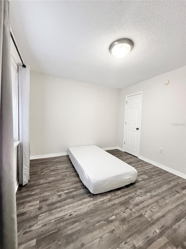 bedroom with dark wood-type flooring and a textured ceiling