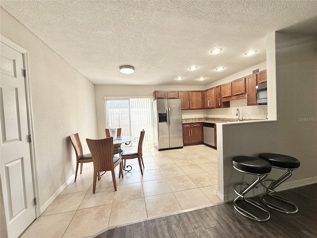 kitchen featuring light tile patterned flooring, appliances with stainless steel finishes, sink, and a textured ceiling