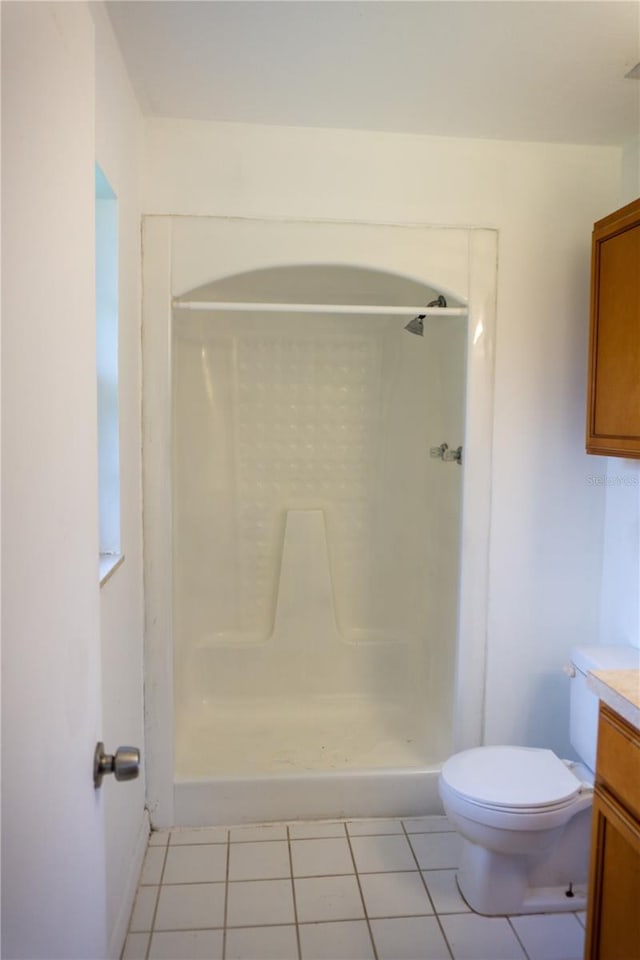 bathroom featuring tile patterned flooring, vanity, toilet, and a shower