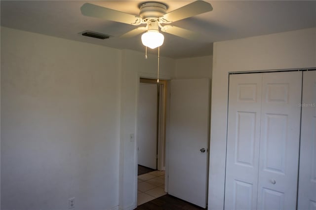 unfurnished bedroom with ceiling fan and a closet