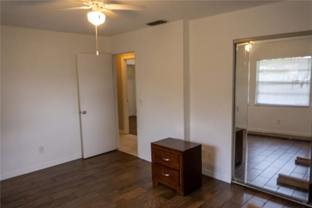 unfurnished bedroom featuring ceiling fan, dark wood-type flooring, and a closet