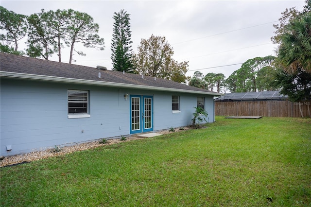 rear view of property featuring a lawn and french doors