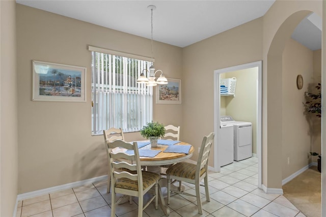 dining space with washer and clothes dryer, light tile patterned flooring, and a chandelier