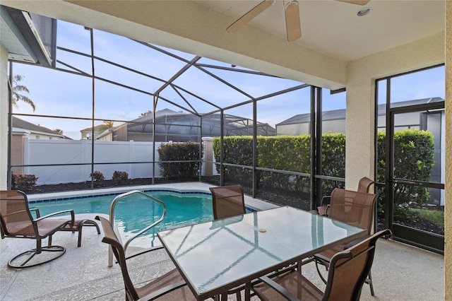 view of swimming pool featuring glass enclosure, ceiling fan, and a patio