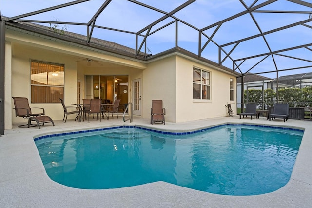 view of swimming pool featuring glass enclosure, ceiling fan, and a patio area