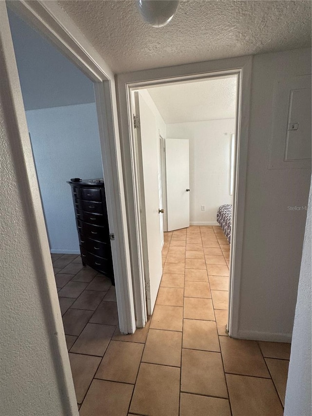 corridor featuring light tile patterned flooring and a textured ceiling