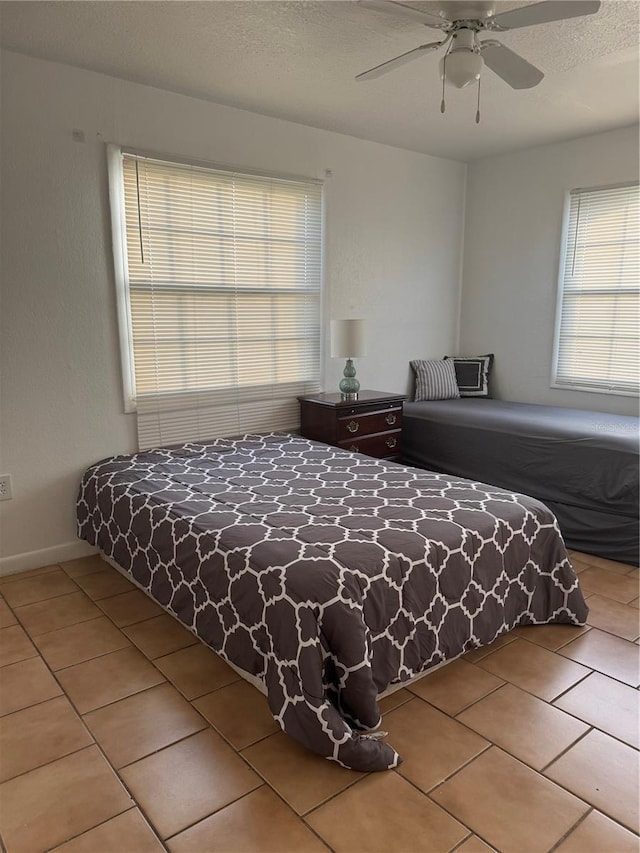 tiled bedroom with ceiling fan and a textured ceiling