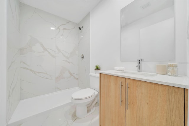 bathroom with vanity, toilet, and tiled shower