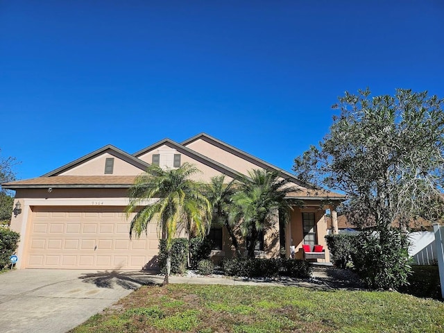 view of front of home featuring stucco siding, driveway, a garage, and fence