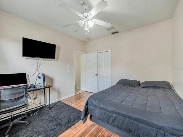 bedroom with a closet, a textured ceiling, ceiling fan, and wood-type flooring