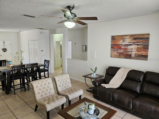 living room with light tile patterned floors, a textured ceiling, and a ceiling fan