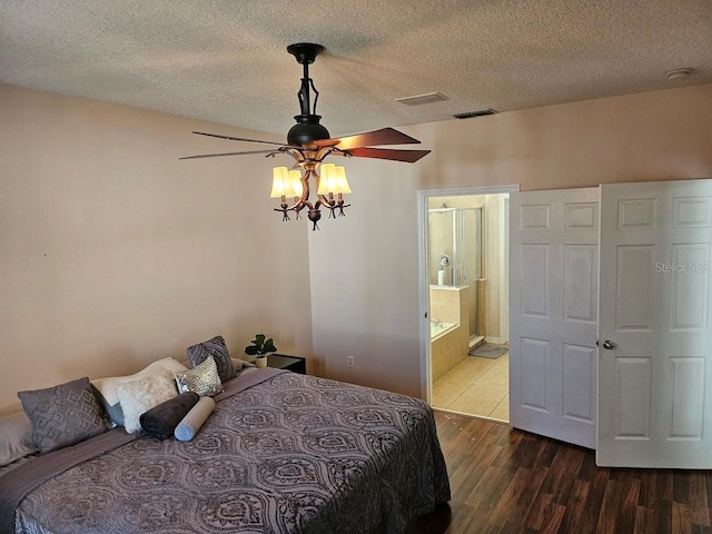 bedroom with ensuite bath, wood finished floors, visible vents, and a textured ceiling