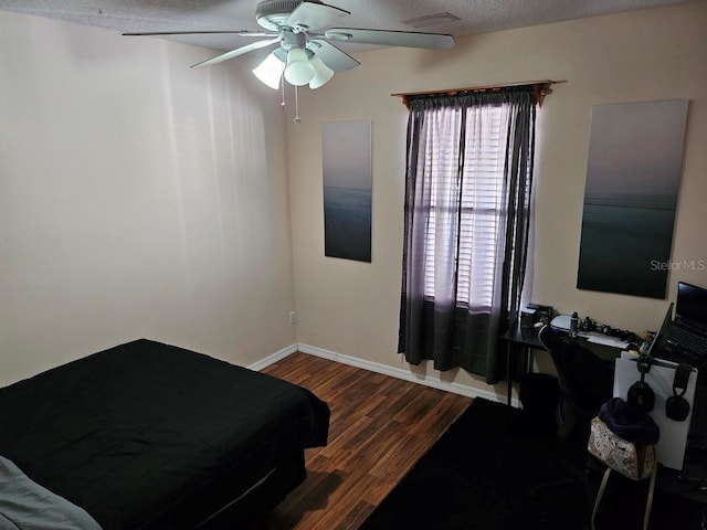 bedroom featuring ceiling fan, a textured ceiling, baseboards, and wood finished floors