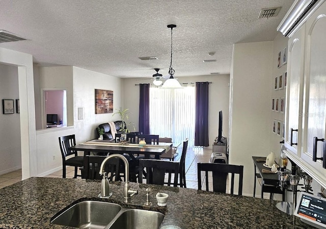 tiled dining room with sink, ceiling fan, and a textured ceiling