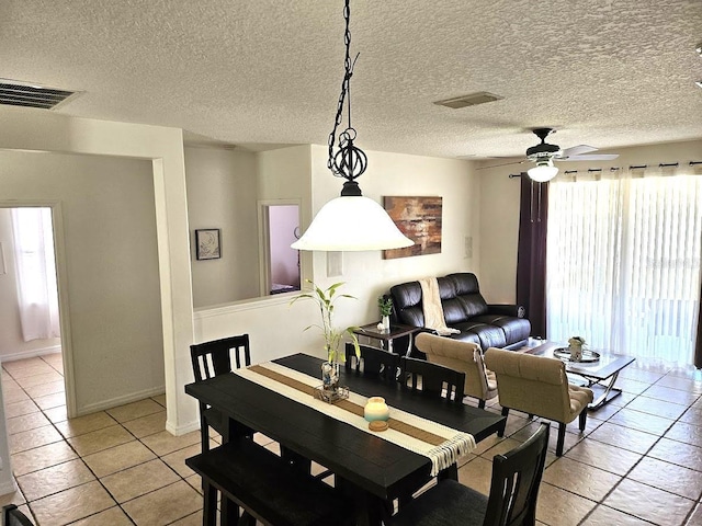 dining area with light tile patterned floors, a ceiling fan, visible vents, and a textured ceiling