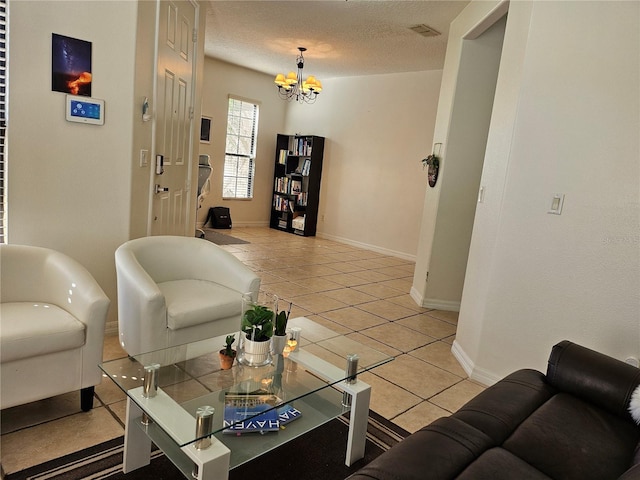 living area featuring a notable chandelier, baseboards, light tile patterned floors, and a textured ceiling