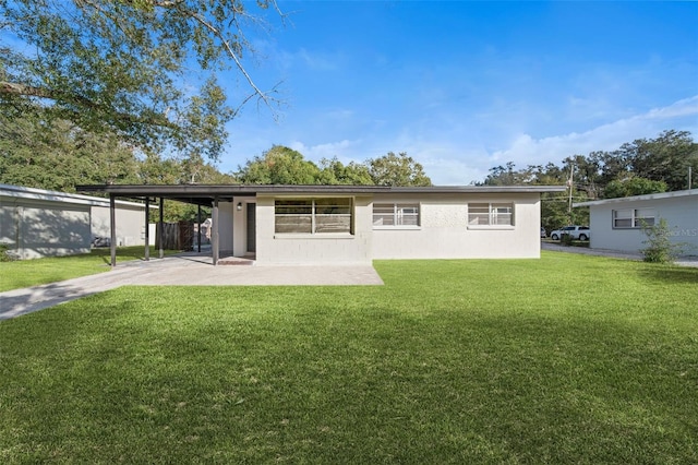 back of property featuring an attached carport, a lawn, and stucco siding