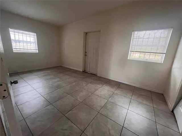 tiled spare room featuring lofted ceiling