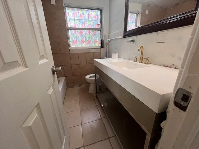 bathroom with toilet, vanity, tile patterned floors, and tile walls