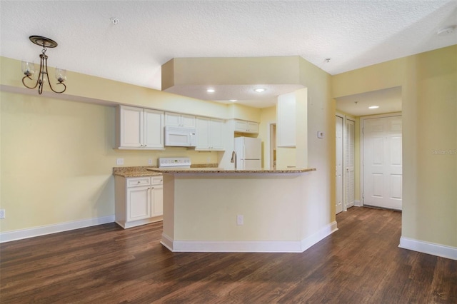 kitchen with white cabinetry, an inviting chandelier, light stone counters, kitchen peninsula, and white appliances