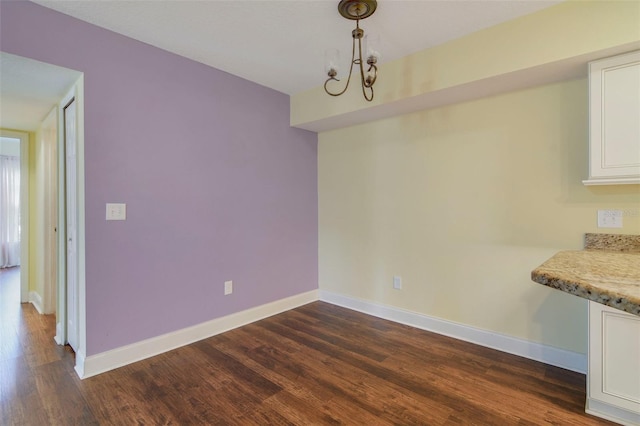 unfurnished dining area featuring dark wood-type flooring and a chandelier