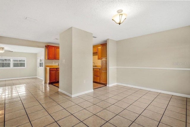 unfurnished living room with ceiling fan, light tile patterned floors, and a textured ceiling